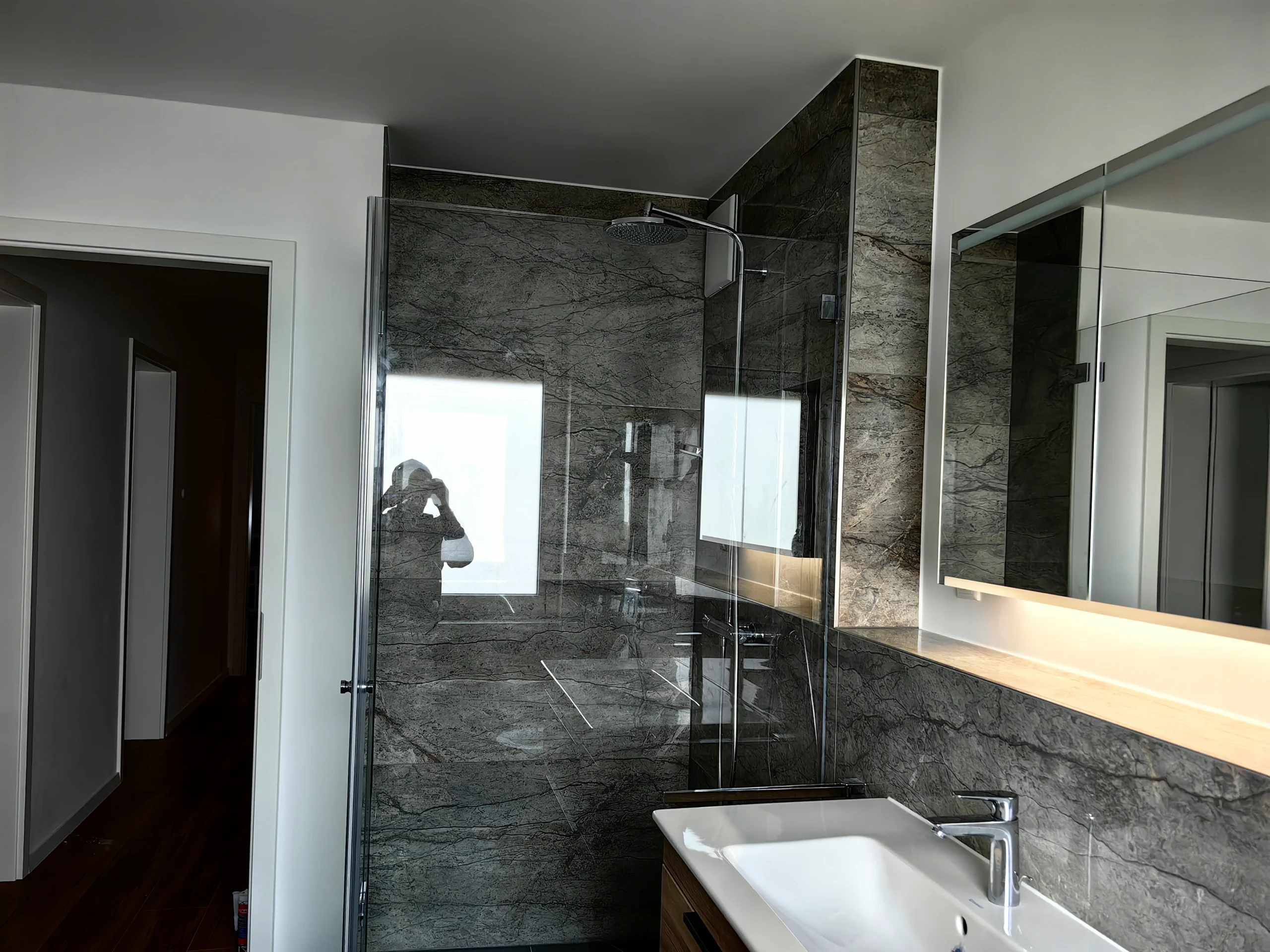 Detailansicht eines sanierten Badezimmers mit Natursteinoptik-Fliesen und bodengleicher Dusche